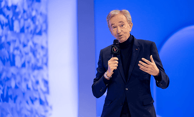 Bernard Arnault tenant microphone sur scène bleue